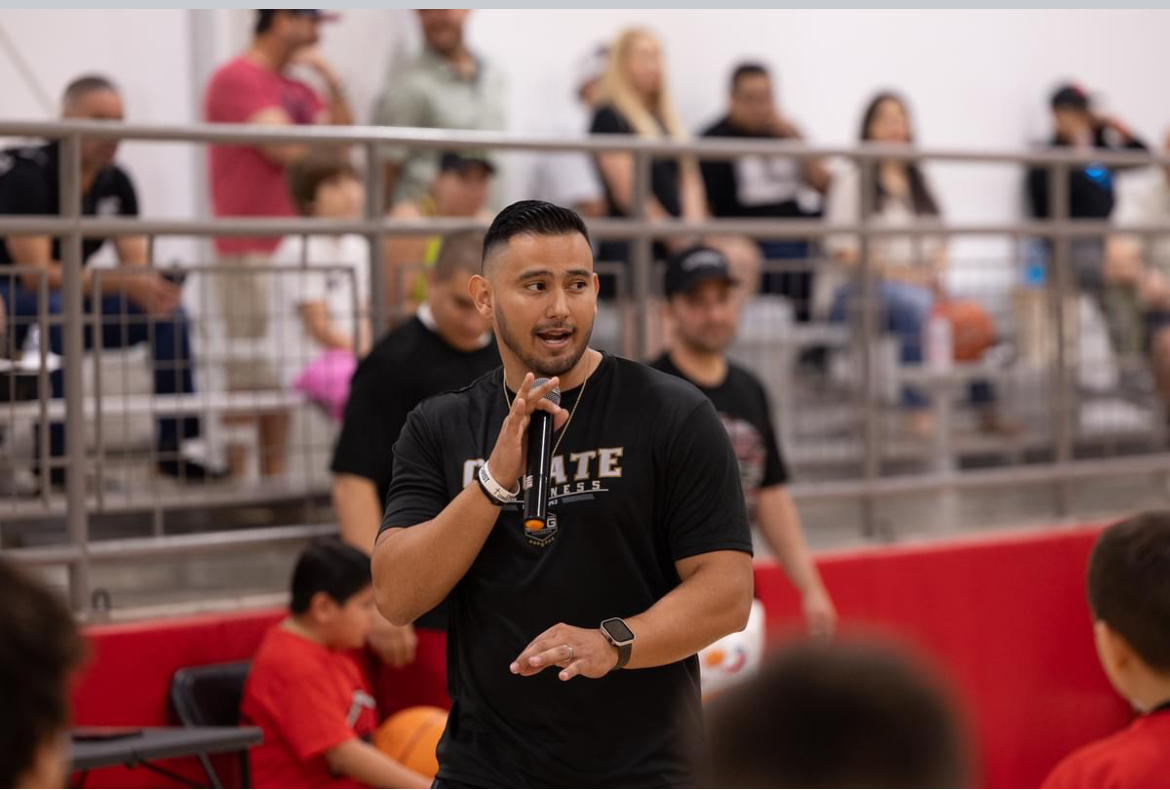 Daniel Rosas speaking with a microphone in a school gym