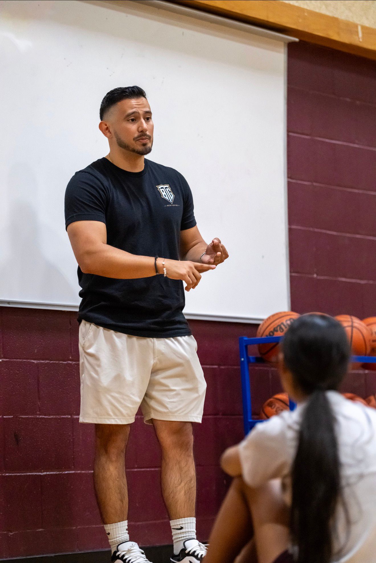 Daniel Rosas mentoring a basketball player at the whiteboard in the gym