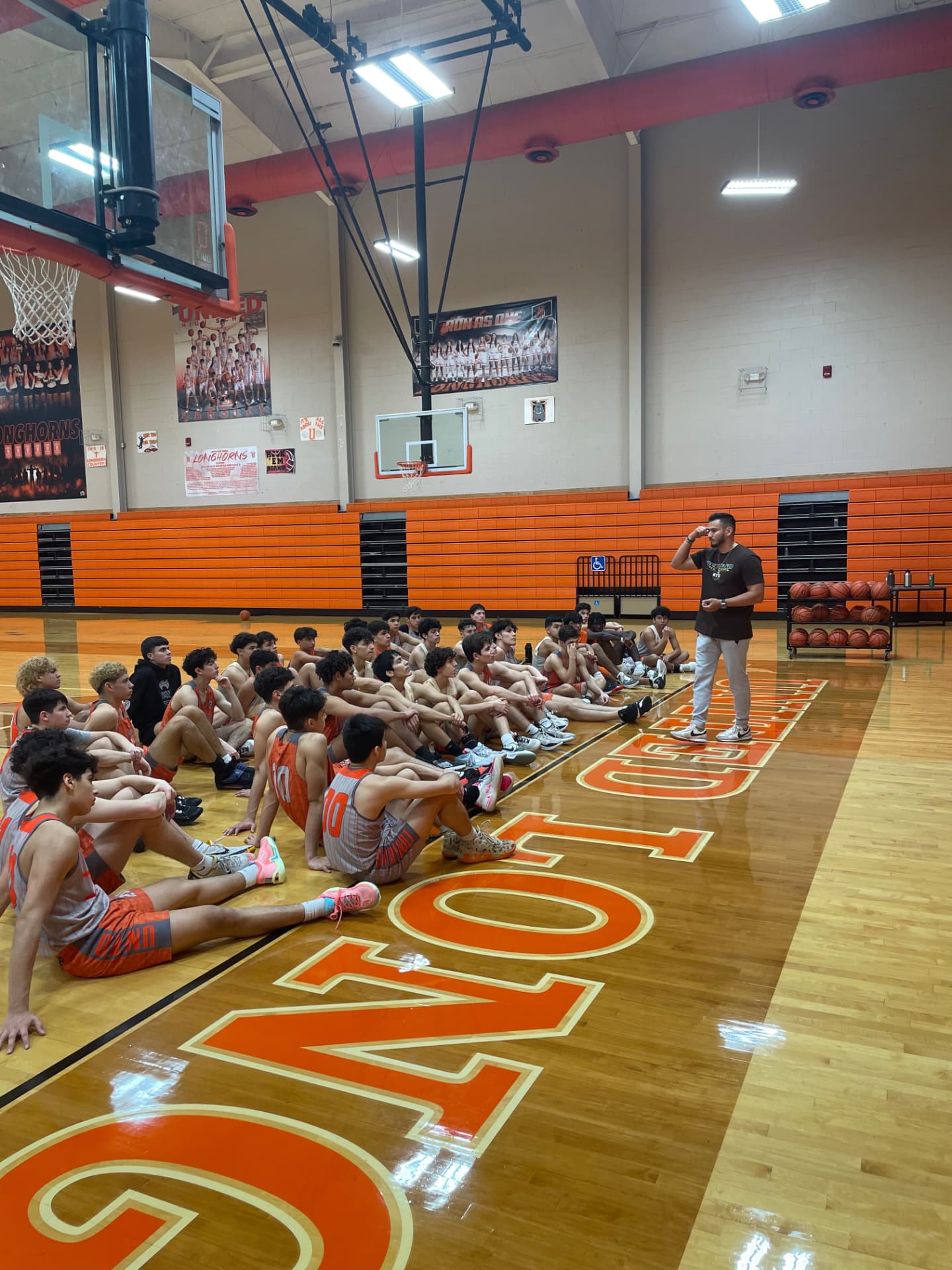 Daniel Rosas speaking to a basketball team in the gym